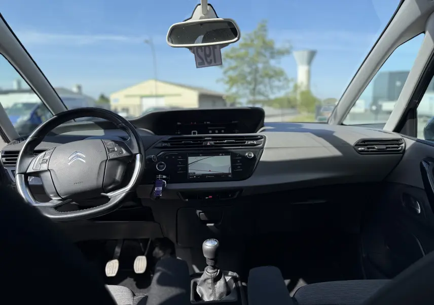 Vue intérieure avant de la Citroën C4 Picasso gris 2017, montrant le volant, tableau de bord et levier de vitesse manuel.