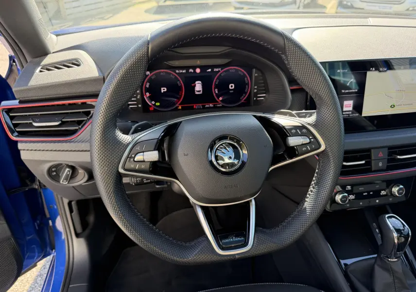 Vue intérieure centrée sur le volant sport en cuir du Skoda Kamiq bleu avec tableau de bord numérique et écran tactile.