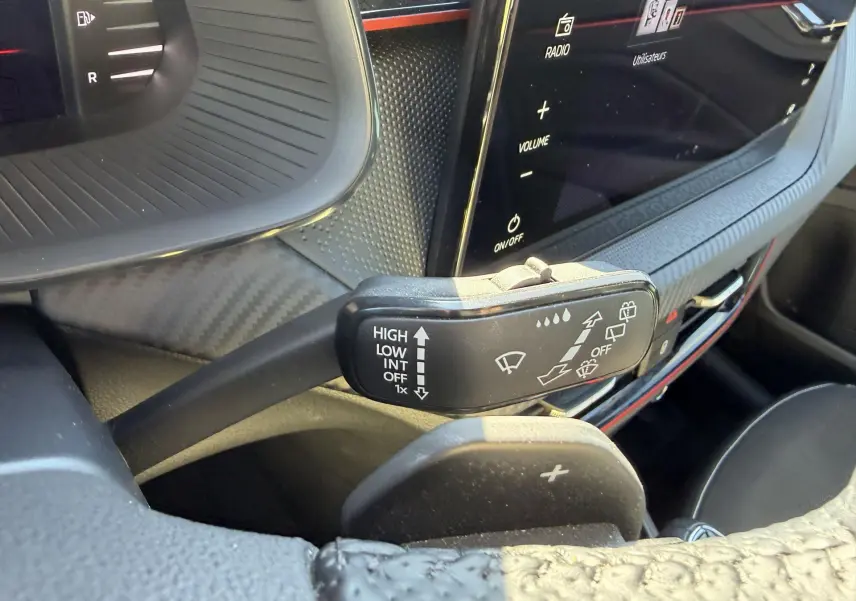 Gros plan sur la commande d’essuie-glace et le volant sport en cuir du Skoda Kamiq 2025, intérieur noir avec écran tactile.