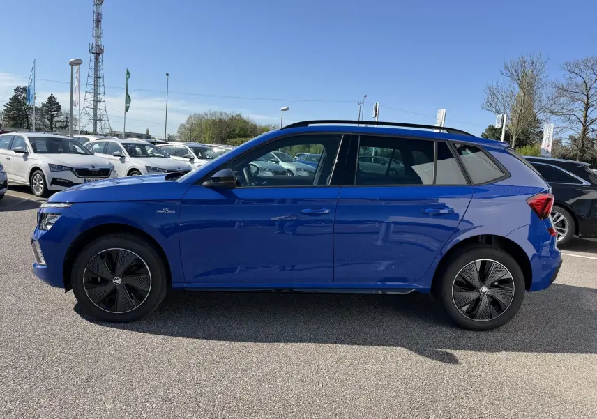 Vue de profil côté gauche d'un Skoda Kamiq bleu avec jantes alliage noires et toit ouvrant panoramique.