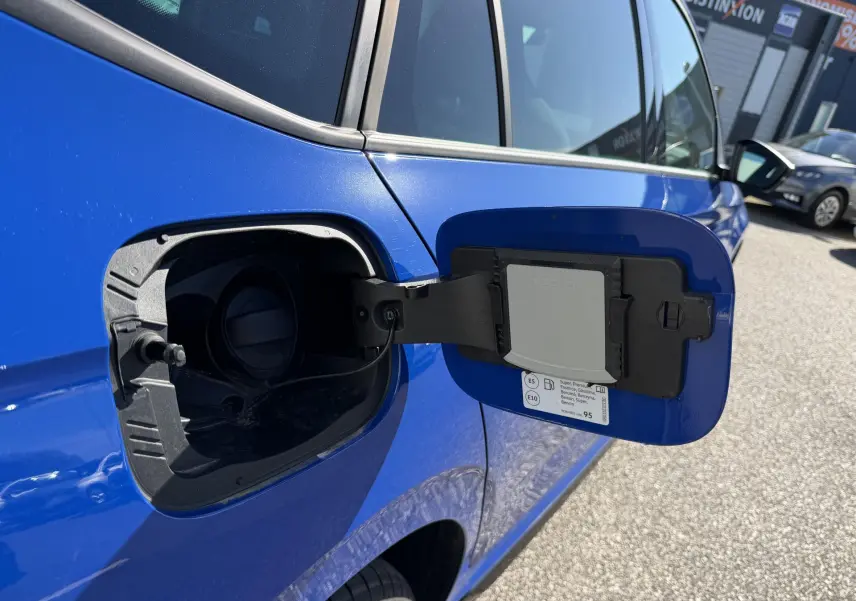 Vue rapprochée de la trappe à carburant ouverte côté gauche d’un Skoda Kamiq bleu 2025 en extérieur.