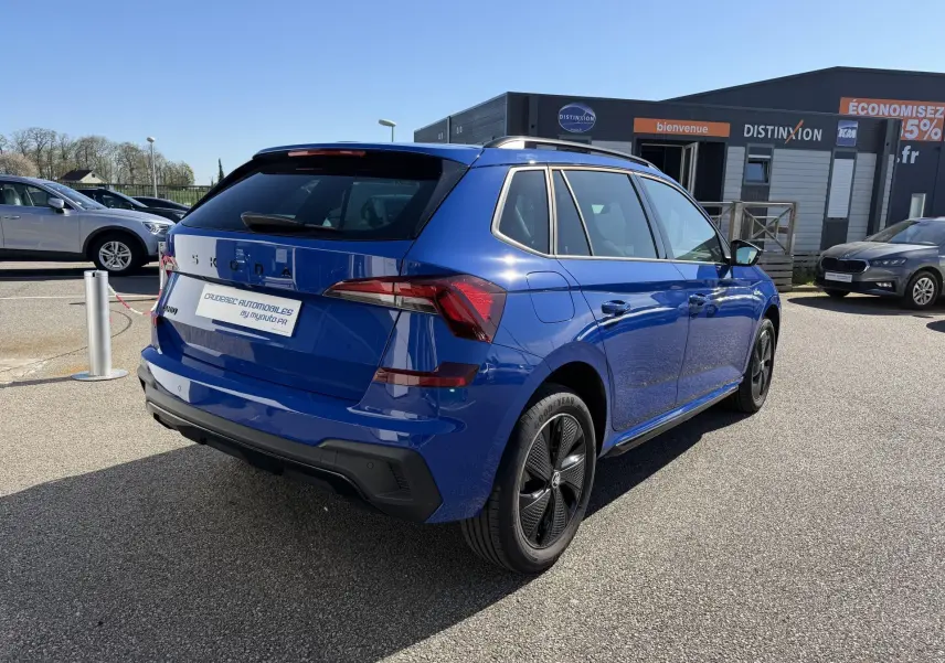 Vue 3/4 arrière droite d'un Skoda Kamiq bleu avec jantes alliage noires sur un parking extérieur.
