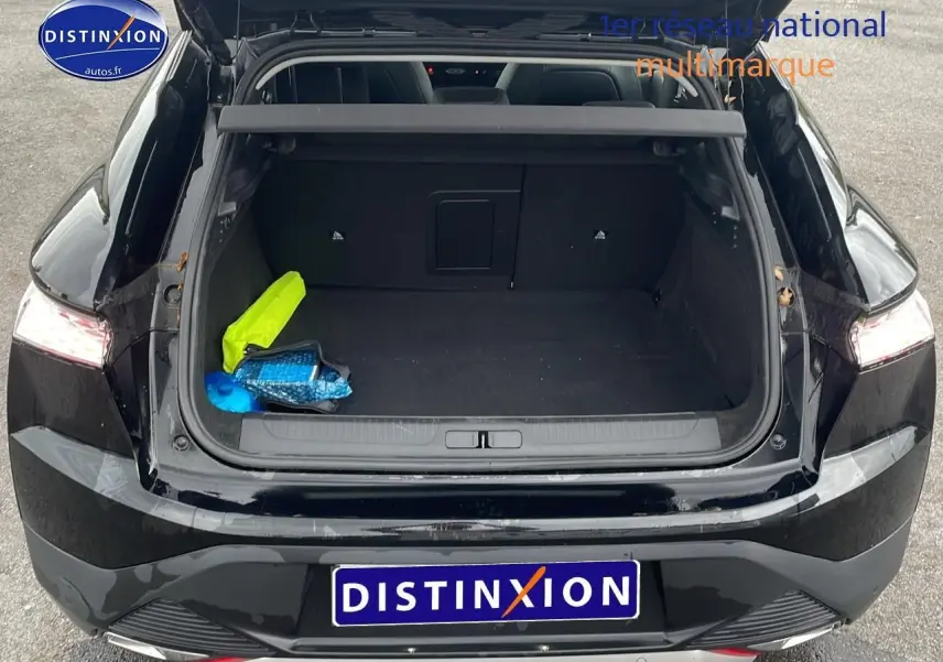 Vue arrière du coffre ouvert d'une DS4 E-tense 225 Cross Trocadero noire avec intérieur spacieux et objets colorés à l'intérieur.