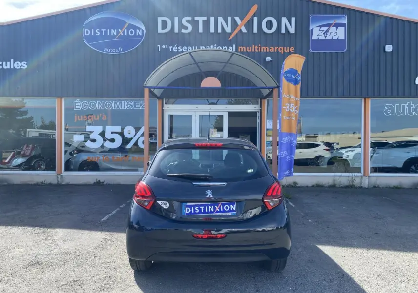 Vue arrière d'une Peugeot 208 gris foncé 2018 stationnée devant un bâtiment avec enseigne Distinxion.