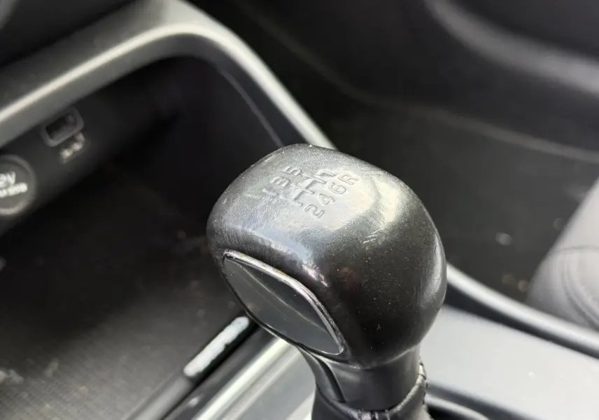 Gros plan sur le pommeau de levier de vitesses manuel noir dans l'habitacle du Volvo XC40 T3 Momentum blanc.