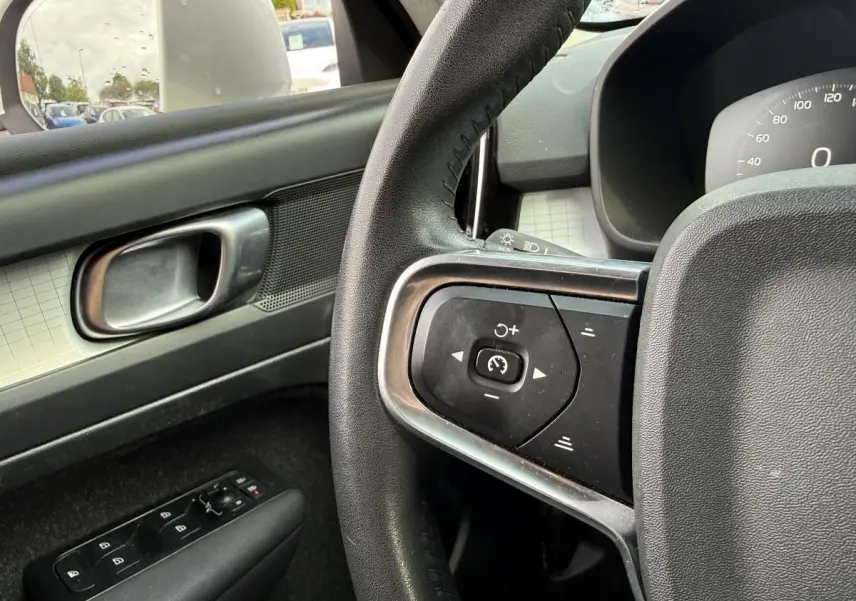 Détail du volant cuir et commandes au volant côté gauche dans l'habitacle du Volvo XC40 blanc.