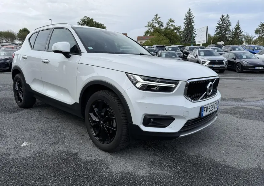 Volvo XC40 blanc en 3/4 avant droit avec jantes alliage noires et calandre chromée sur parking extérieur.