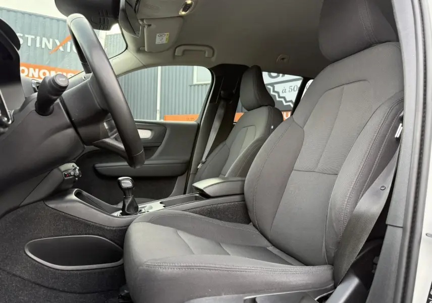 Intérieur côté conducteur du Volvo XC40 blanc 2020, sièges tissu anthracite et levier de vitesses manuel visible.