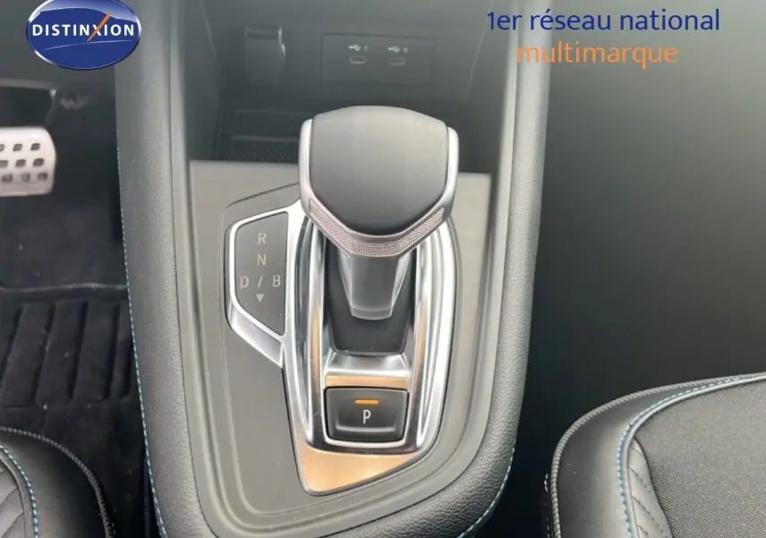 Gros plan sur la commande de boîte automatique noire et chrome dans l'habitacle du Renault Symbioz blanc nacré.