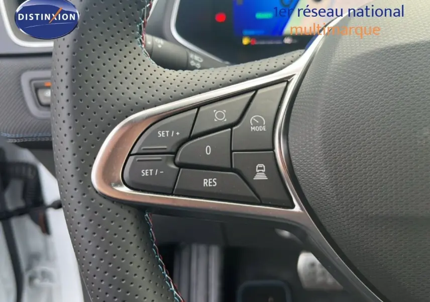 Gros plan sur la partie gauche du volant perforé du Renault Symbioz blanc nacré, avec commandes de régulateur de vitesse.