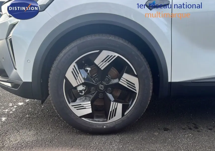 Gros plan sur la roue avant gauche d’un Renault Symbioz blanc nacré avec jante au design noir et argent.