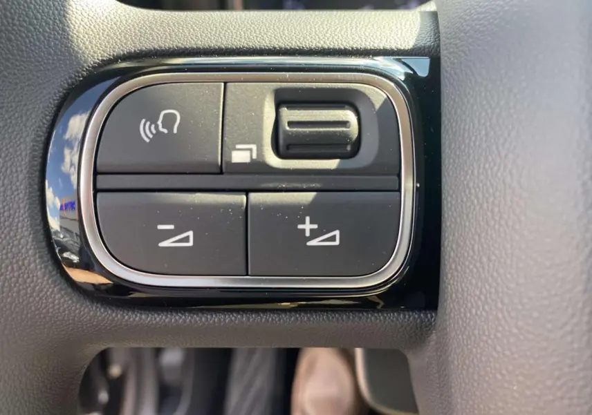 Gros plan sur les commandes de volume et de reconnaissance vocale sur le volant du Citroën C3 Aircross noir 2021.