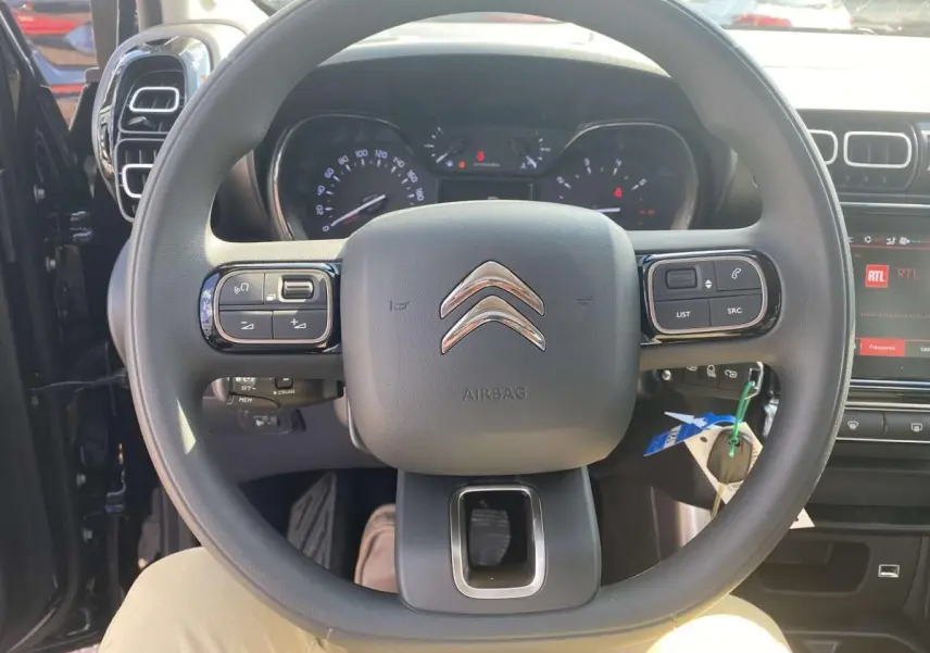 Vue rapprochée du volant noir de la Citroën C3 Aircross 2021, avec commandes intégrées et tableau de bord visible.