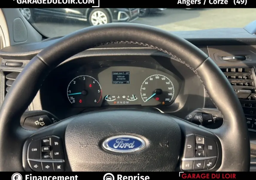 Vue intérieure centrée sur le volant cuir Ford noir et le tableau de bord du Transit Custom blanc 2023.