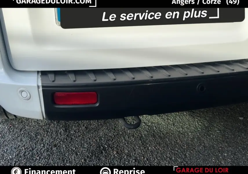 Gros plan sur le pare-chocs arrière noir et blanc du Ford Transit Custom avec feu rouge et crochet d'attelage visible.