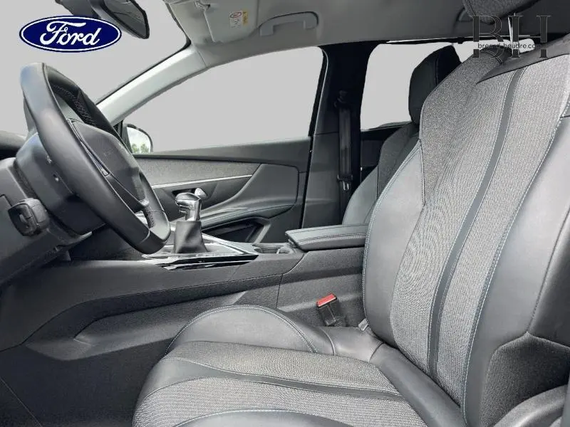 Vue intérieure côté conducteur du Peugeot 5008 1.5 BlueHDi 130ch avec sièges en tissu et cuir noir, volant multifonction et levier de vitesse manuel.