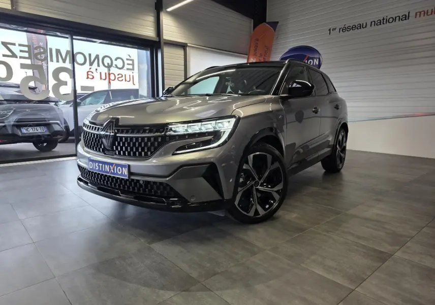 Renault Austral gris foncé en 3/4 avant droit, avec calandre à damier et jantes alliage noires diamantées.
