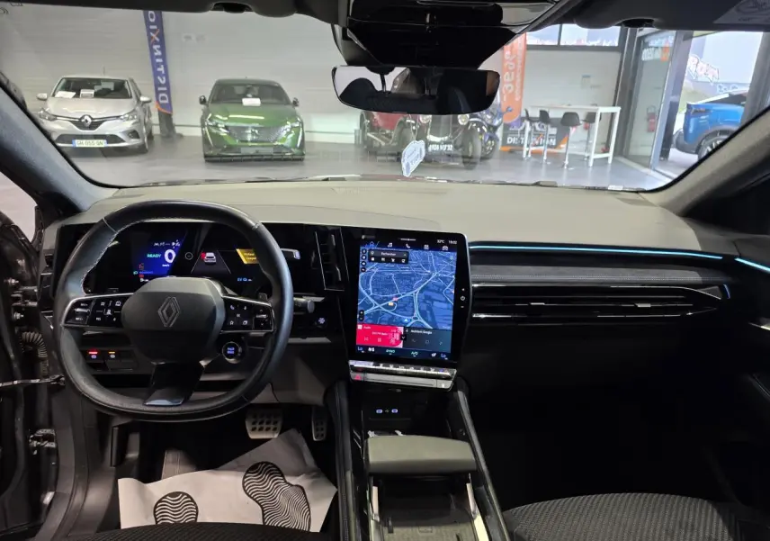 Vue intérieure avant du Renault Austral gris foncé, avec tableau de bord digital et écran tactile central vertical.