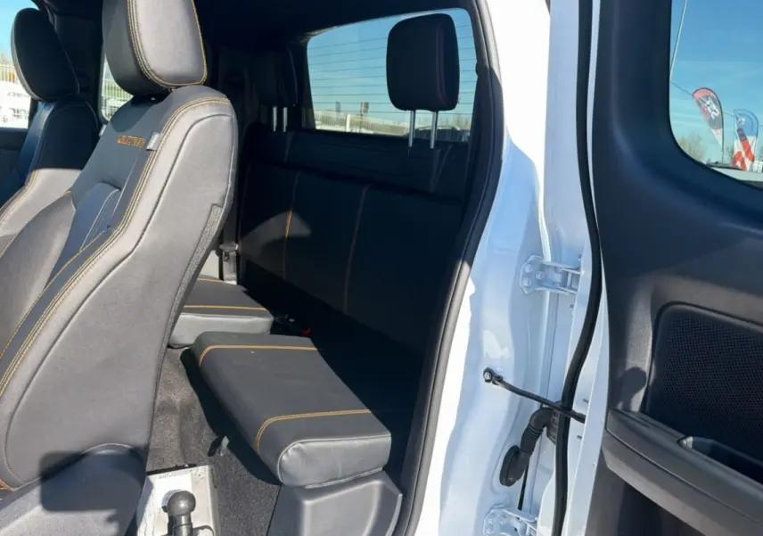 Vue intérieure côté droit du Ford Ranger blanc 2025, montrant les sièges arrière en tissu noir avec surpiqûres orange.