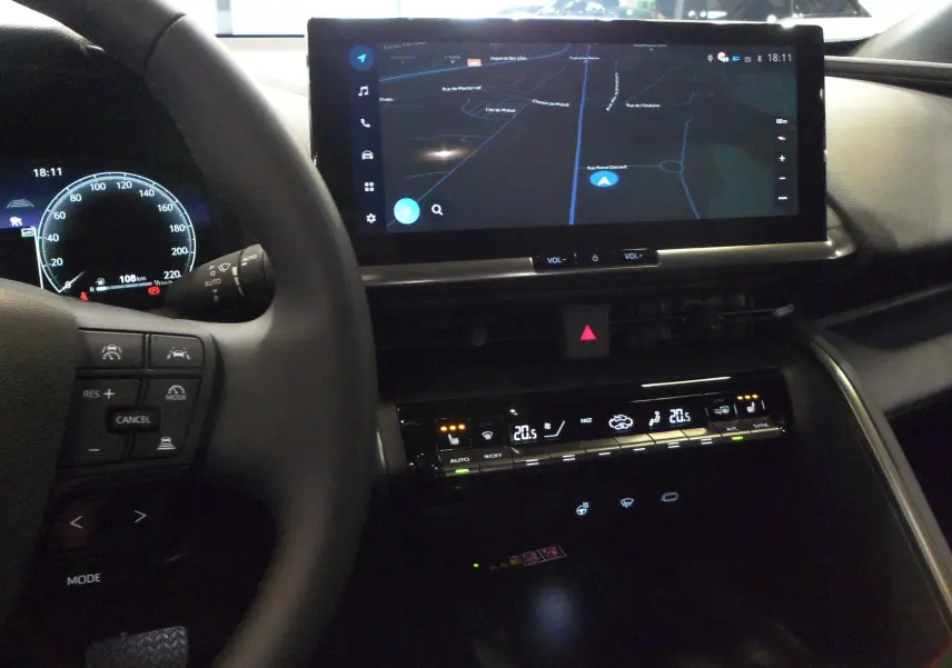 Tableau de bord du Toyota C-HR hybride 2025 avec écran tactile de navigation et commandes climatisation digitales.