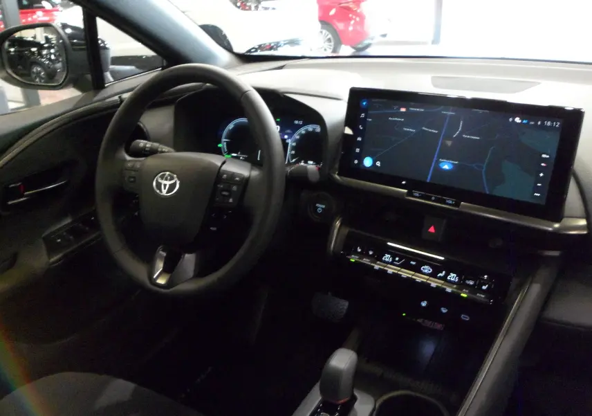 Intérieur du Toyota C-HR hybride 2025 vu côté conducteur, avec tableau de bord numérique et grand écran tactile central.