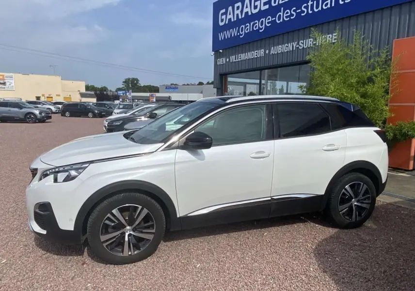 Peugeot 3008 blanc nacré en profil côté gauche, toit noir et jantes alliage bi-ton devant un garage.