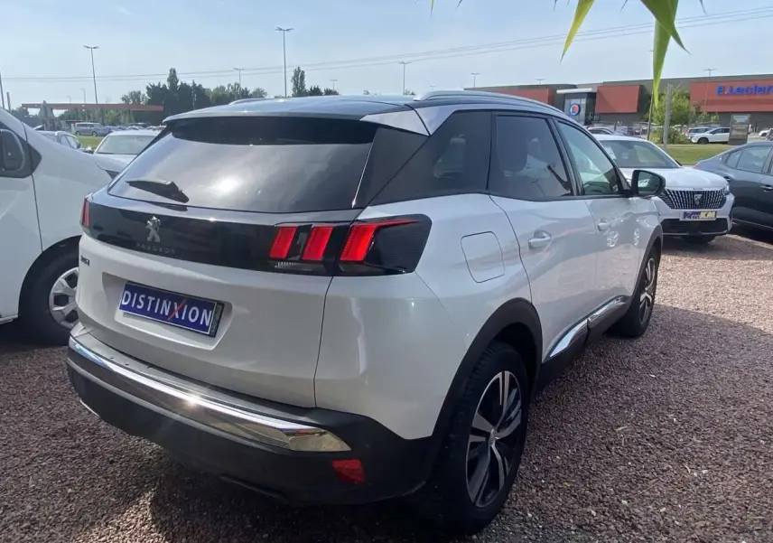 Peugeot 3008 blanc nacré vue 3/4 arrière droit avec toit noir et vitres surteintées sur parking.