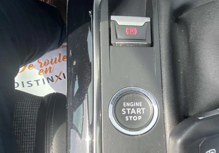 Gros plan sur le bouton moteur start/stop et frein à main électronique dans l'habitacle noir du Peugeot 3008 blanc.