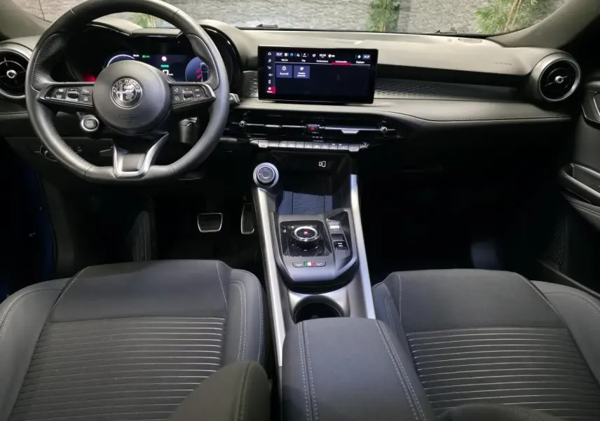 Vue intérieure avant de l'Alfa Romeo Tonale 2025 bleu, volant cuir sport et écran tactile central large.