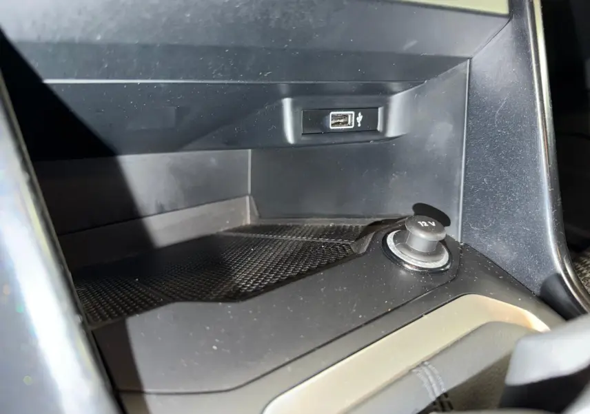 Gros plan intérieur sur la prise 12V et port USB du Volkswagen T-Roc bleu, version 1.0 TSI 115 Lounge.