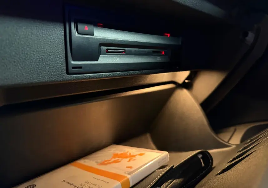 Gros plan sur le compartiment de rangement côté passager du Volkswagen T-Roc 2019, intérieur noir avec manuel d'utilisation.