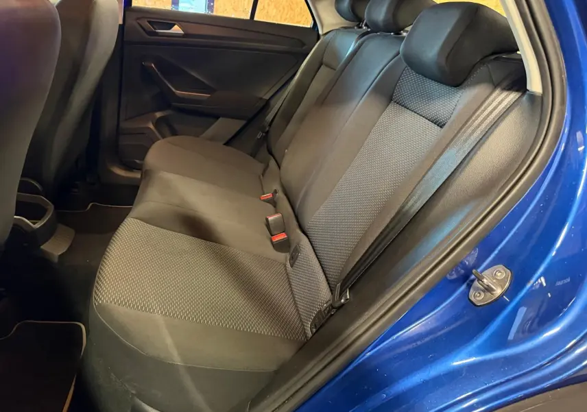 Vue intérieure côté droit de la banquette arrière grise du Volkswagen T-Roc bleu avec ceintures et appuis-tête visibles.