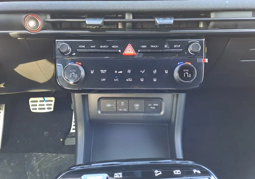 Vue rapprochée du tableau de bord noir du Hyundai Tucson 2025, mettant en valeur la console centrale avec commandes climatisation et connectiques.