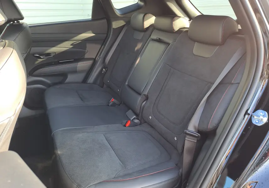 Vue intérieure côté droit des sièges arrière noirs en cuir et alcantara avec surpiqûres rouges du Hyundai Tucson 2025 Abyss Black.