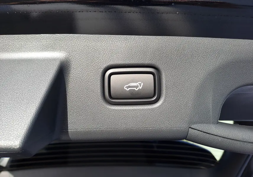 Bouton d'ouverture électrique du hayon sur la garniture intérieure noire du coffre d'un Hyundai Tucson 2025 Abyss Black.