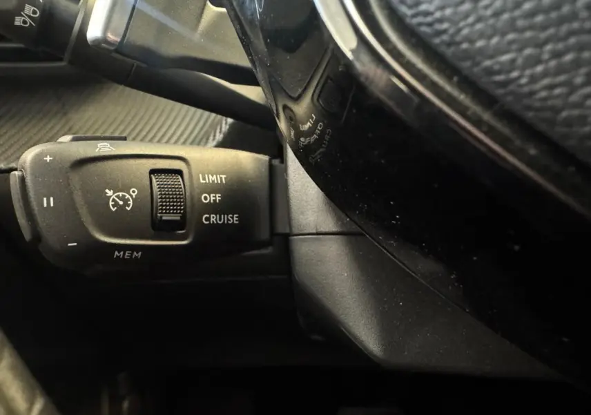 Gros plan sur la commande de régulateur de vitesse à gauche du volant du Peugeot 2008 Hybrid 145 e-DCS6 Allure gris.
