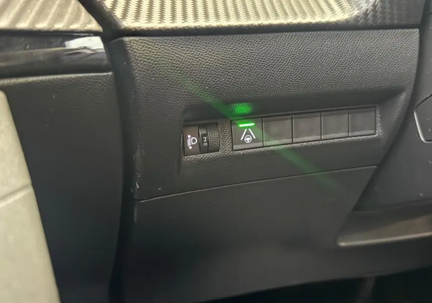 Gros plan sur les commandes latérales gauche du tableau de bord noir du Peugeot 2008 Hybrid 145 e-DCS6 Allure 2025.
