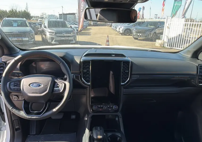 Vue intérieure frontale du Ford Ranger Wildtrak 2025 blanc, avec volant cuir multifonctions et écran tactile vertical.
