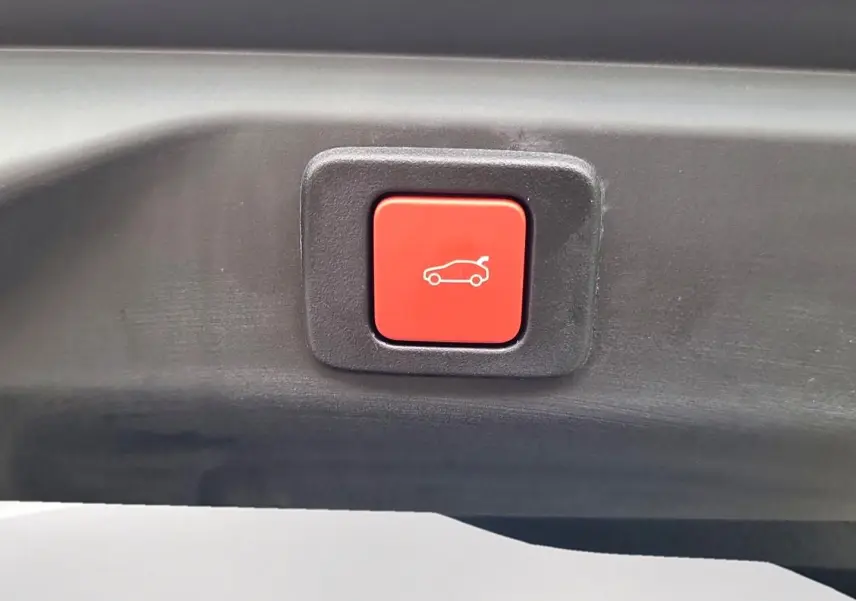 Bouton rouge de fermeture électrique du hayon sur un Peugeot 3008 blanc toit noir, vue en gros plan.