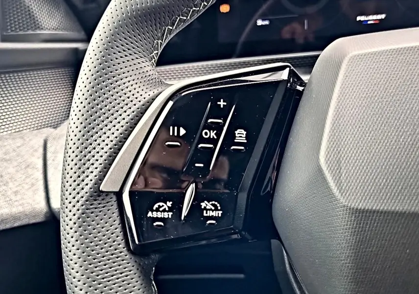 Gros plan sur la commande gauche du volant cuir perforé du Peugeot 3008 blanc toit noir, avec boutons multifonctions.