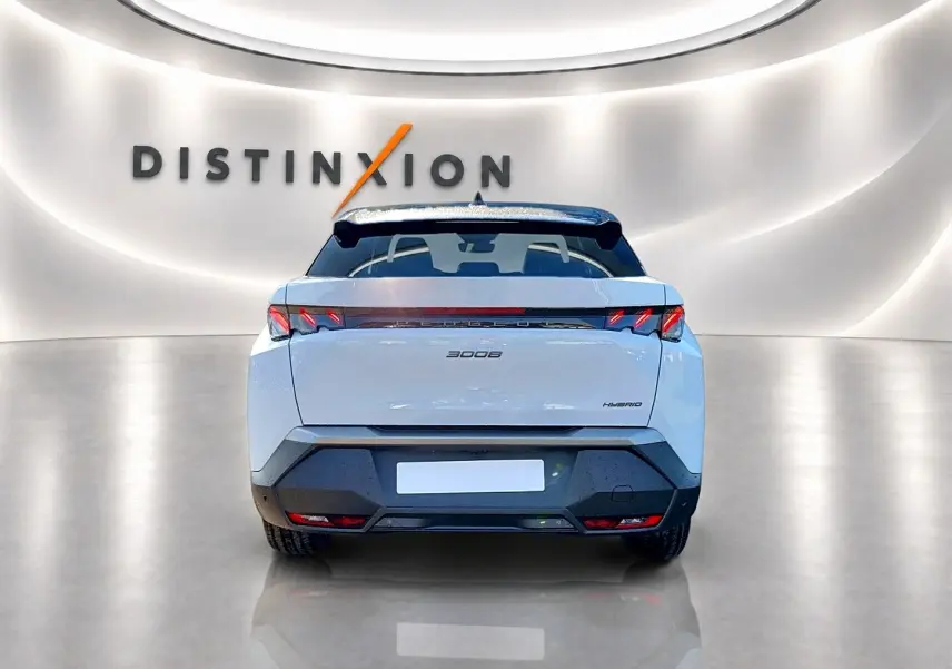 Vue arrière d'un Peugeot 3008 hybride blanc avec toit noir, feux LED et becquet arrière dans un showroom lumineux.