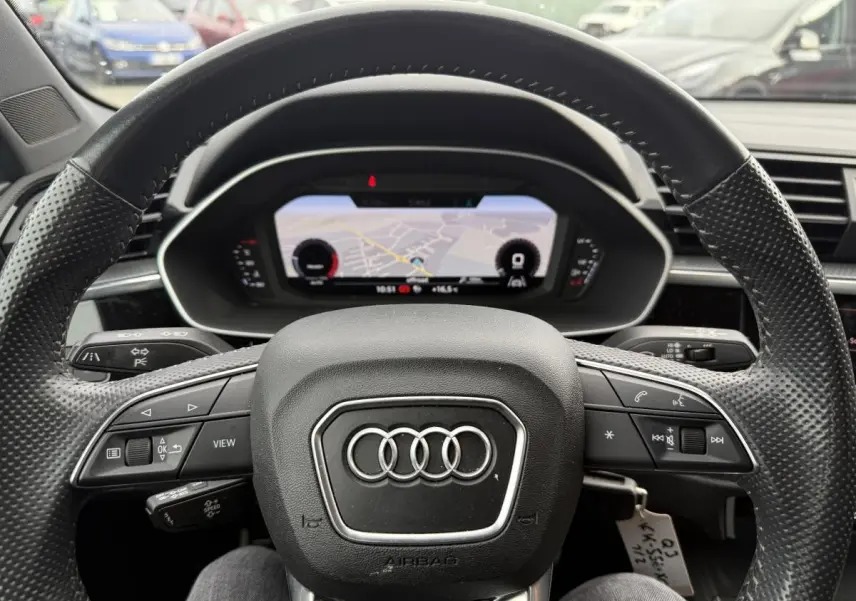 Vue rapprochée du volant en cuir noir perforé et du tableau de bord numérique d'un Audi Q3 Quattro 2019.