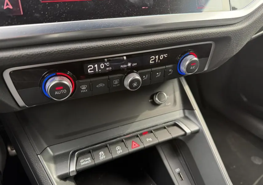 Gros plan sur la console centrale noire de l'Audi Q3 S Line 2019 avec commandes de climatisation automatique et boutons multifonctions.