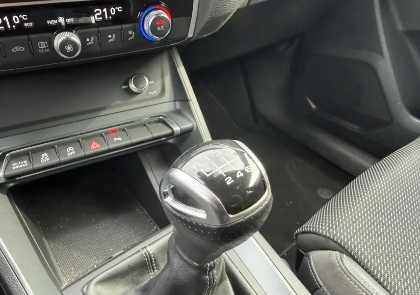 Le levier de vitesses manuel noir de l'Audi Q3 S Line 2019 avec commandes de climatisation en arrière-plan.
