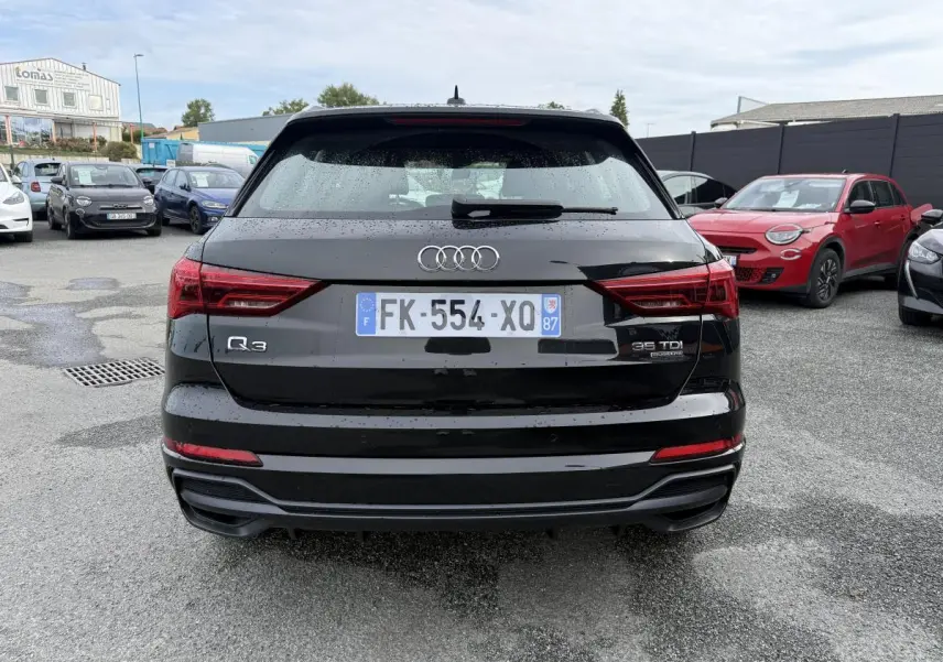 Vue arrière d'un Audi Q3 noir 2019 avec badges Quattro et 35 TDI, stationné sur un parking humide.