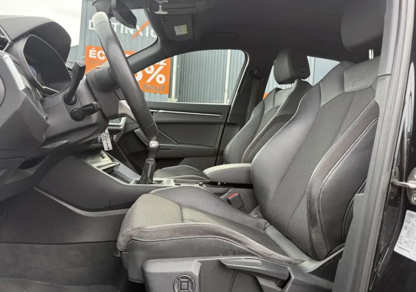 Intérieur noir de l'Audi Q3 S Line 2019 vu côté gauche, avec sièges sport en tissu et similicuir et volant cuir.