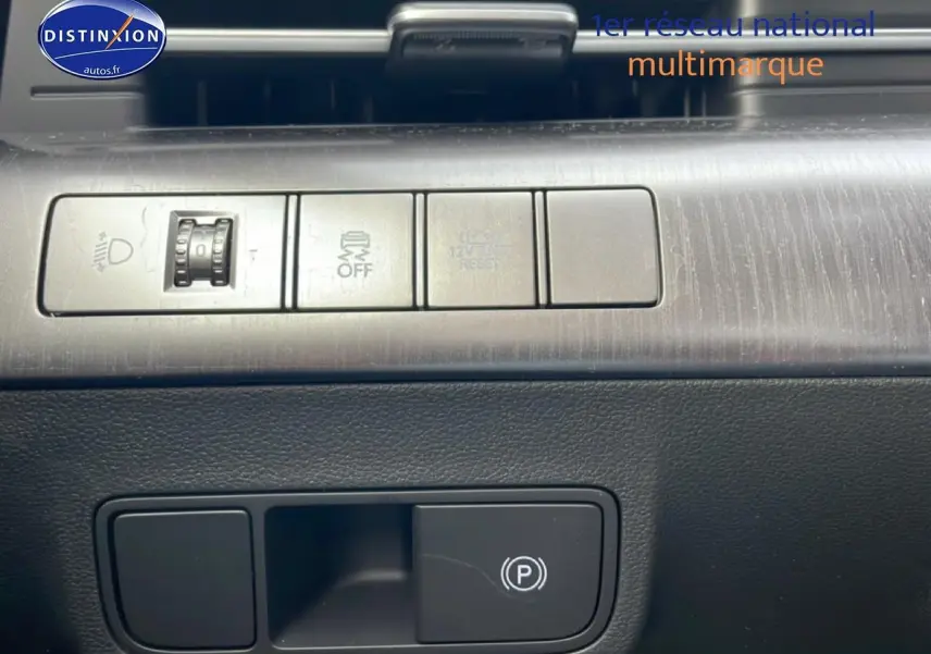 Gros plan sur les commandes intérieures du Hyundai Kona 2025, avec bouton frein à main électrique et réglage éclairage.