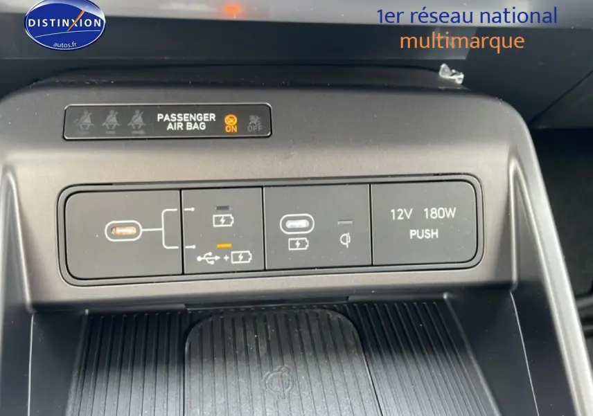 Vue rapprochée du panneau de commandes USB, prise 12V et indication airbag passager du Hyundai Kona bleu 2025.