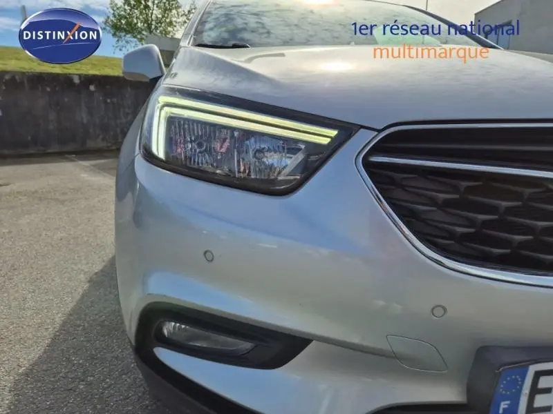 Gros plan sur l'avant droit gris minéral de l'Opel Mokka X 2018 avec phares LED et calandre distinctive.