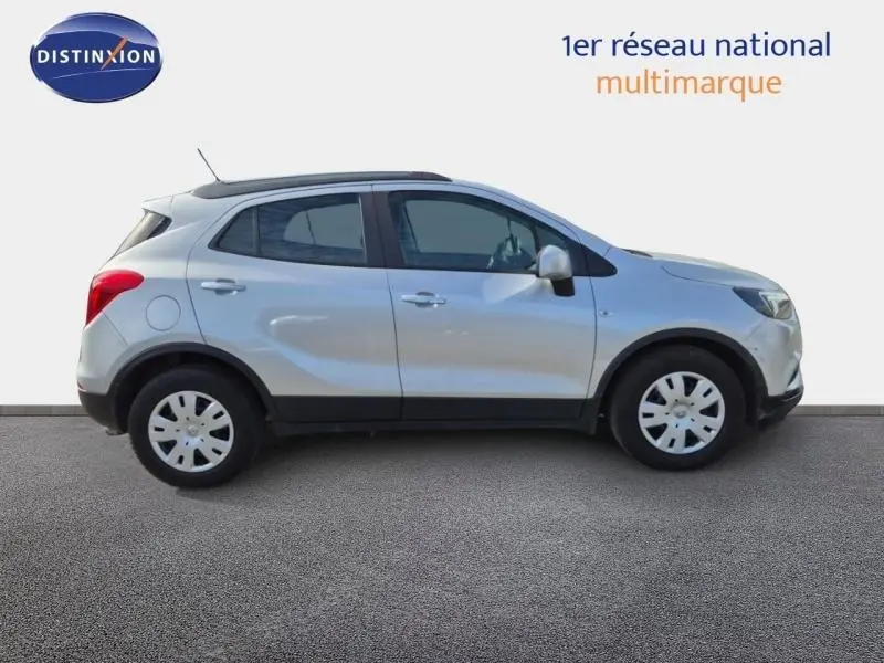 Vue de profil côté gauche d'un Opel Mokka X gris minéral avec jantes acier et rétroviseurs argentés.
